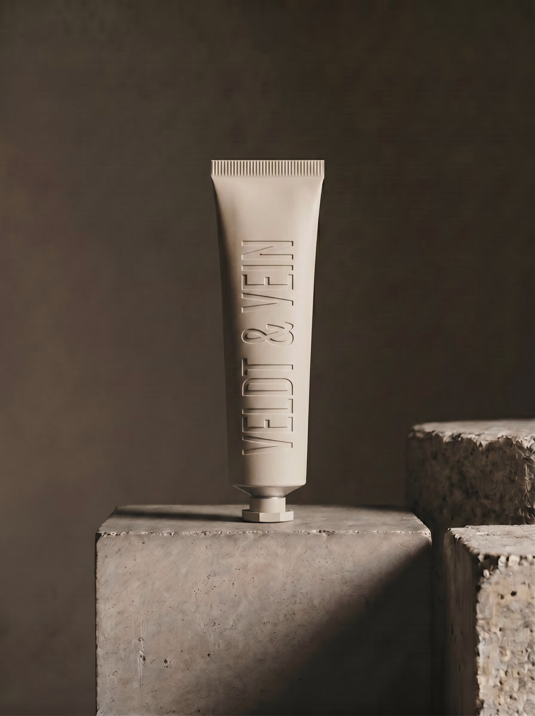 The Marula Peptide Hand & Nail Renewal — debossed aluminium tube on a concrete plinth.